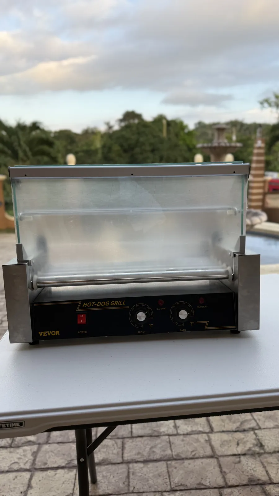 Hot-dog grill with its glass cover raised