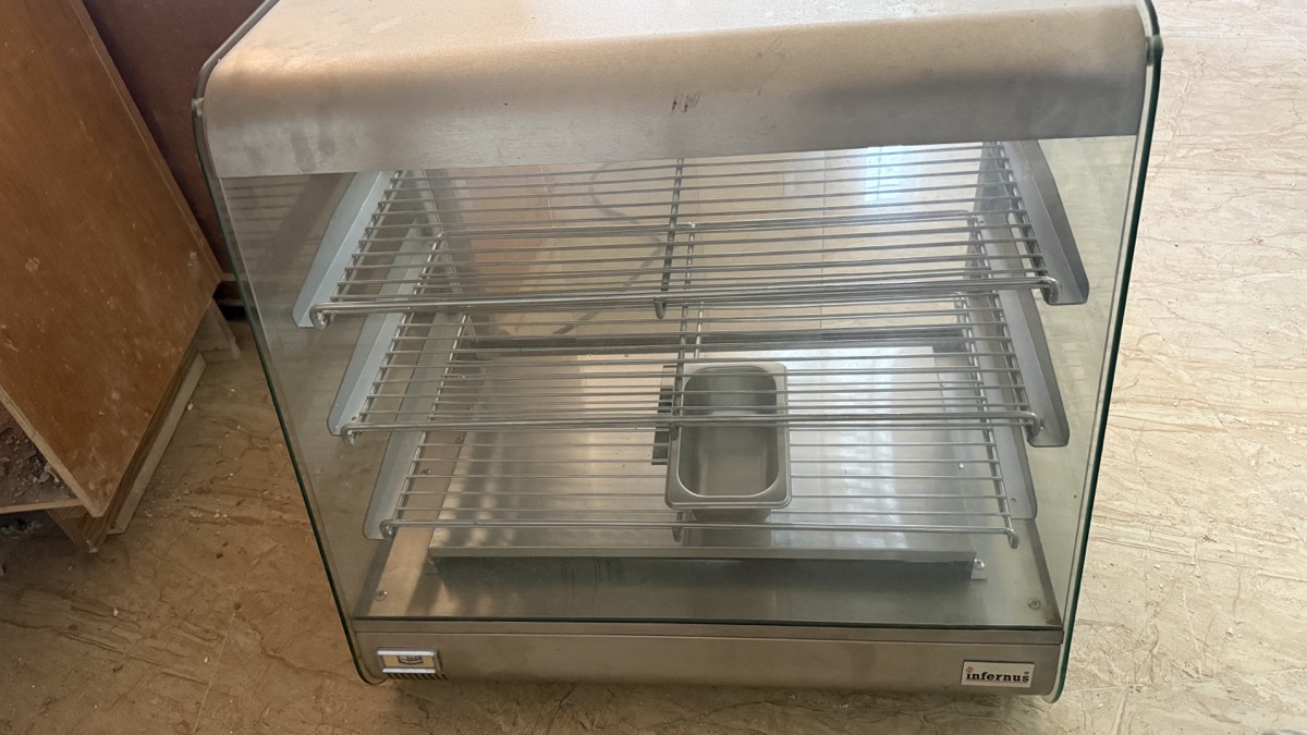 Angled view of the glass-fronted Infernus patty warmer and its removable humidity pan